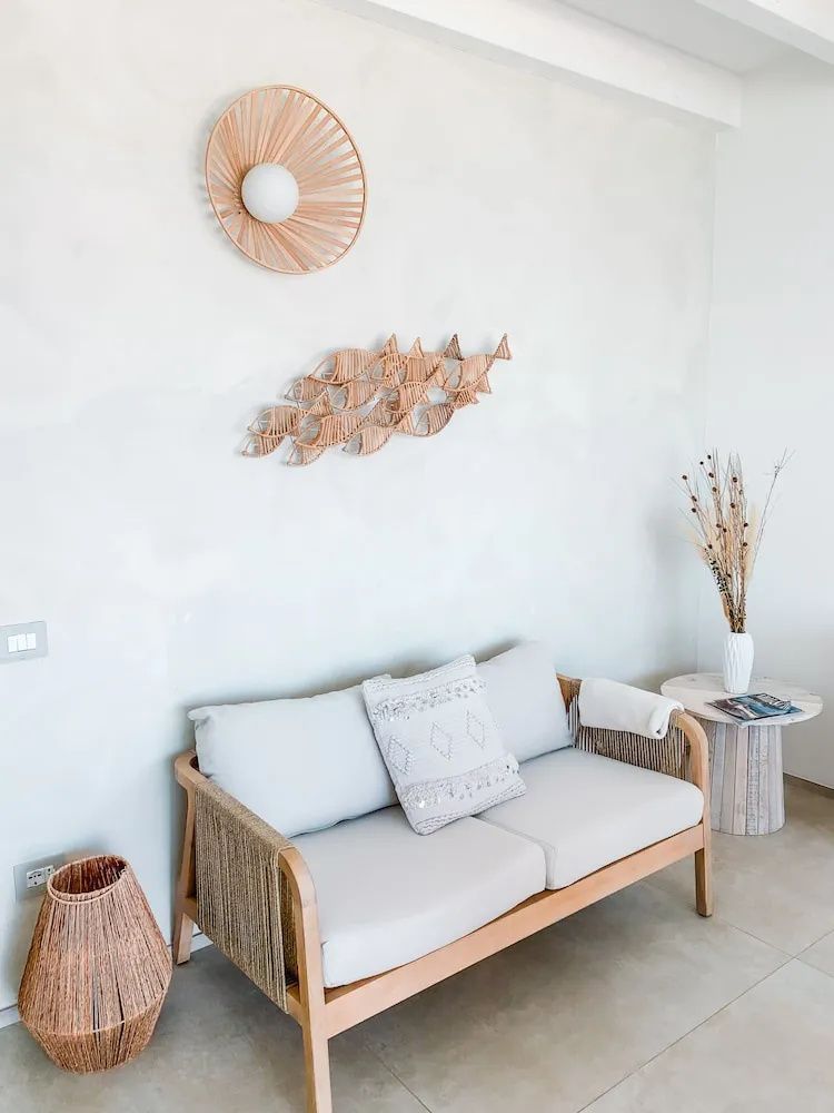 Sitzbereich mit kleinem Sofa, Flechtlampe und hölzerner Fischdekoration an der Wand.