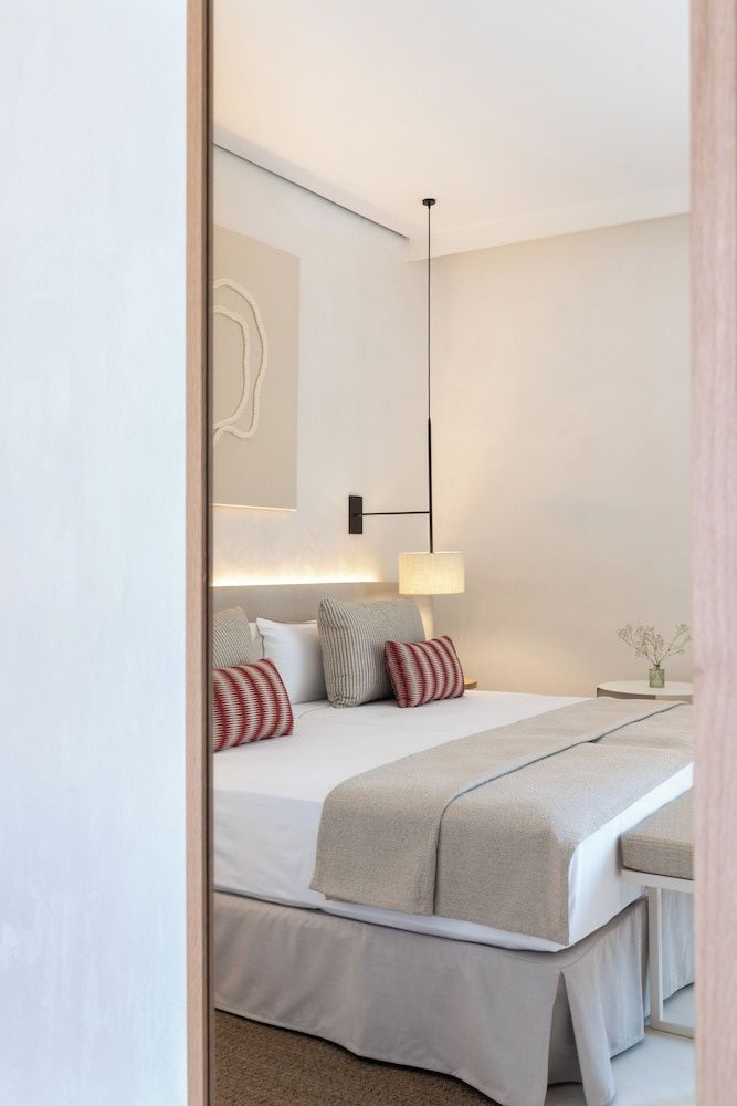 Hell eingerichtetes Hotelzimmer mit Doppelbett und modernen Nachttischlampen.