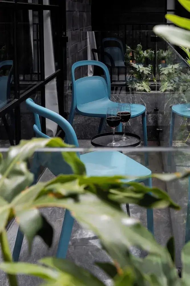 Blaue Stühle und ein kleiner Tisch mit Rotweingläsern auf einem schmalen Balkon