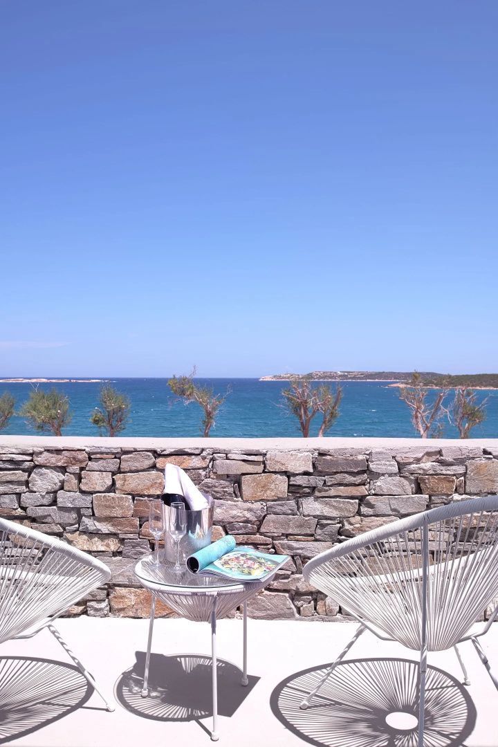 Terrasse mit Natursteinmauer und Blick auf das blaue Meer unter klarem Himmel.