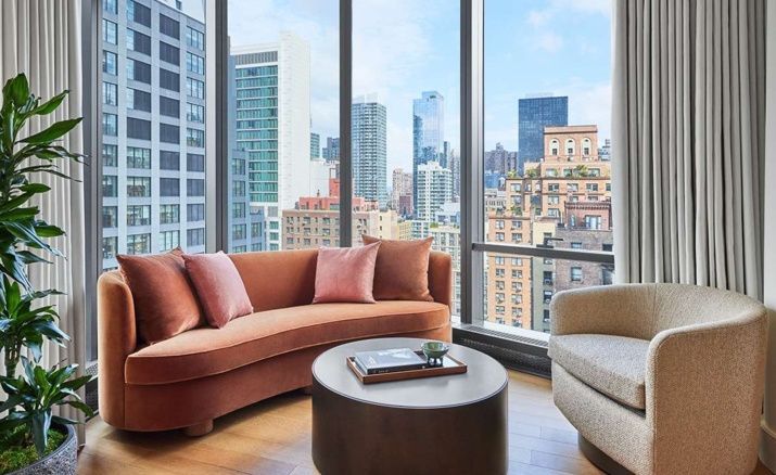 Sitzbereich mit gebogenem Sofa an einem großen Fenster mit Blick auf die Skyline der Stadt.