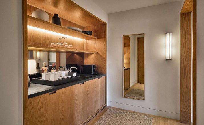Holznische mit integrierter Minibar, Kaffeemaschine, Gläsern und hohem Wandspiegel.