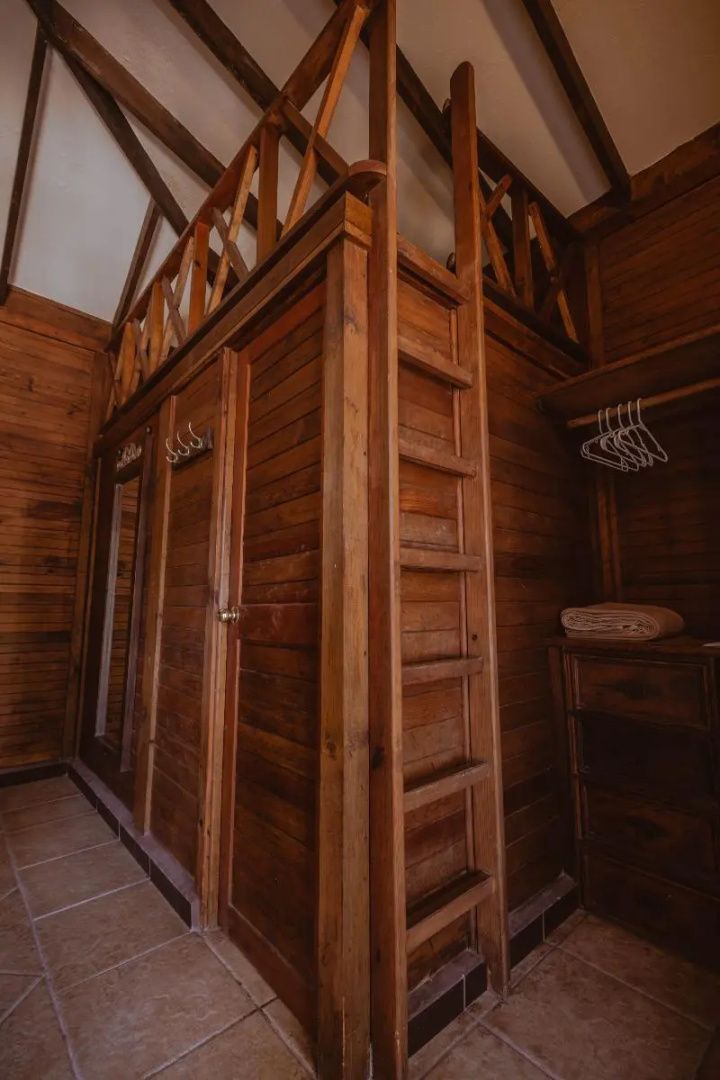 Holzschrank und eine Leiter zu einer hölzernen Empore im Zimmer.