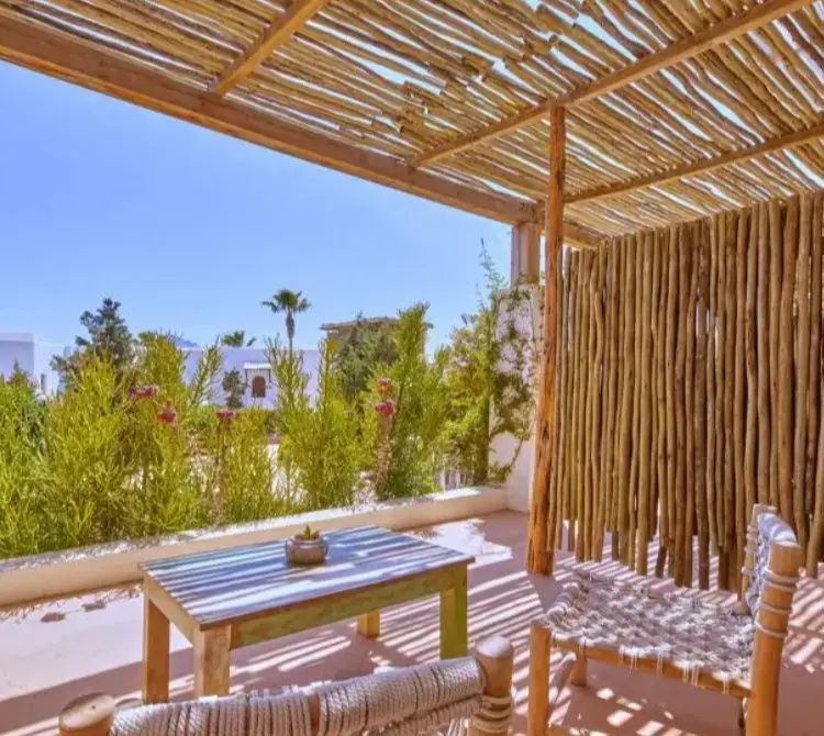 Überdachte Terrasse mit Holzpergola, Sitzgelegenheiten und Blick auf die Bepflanzung.