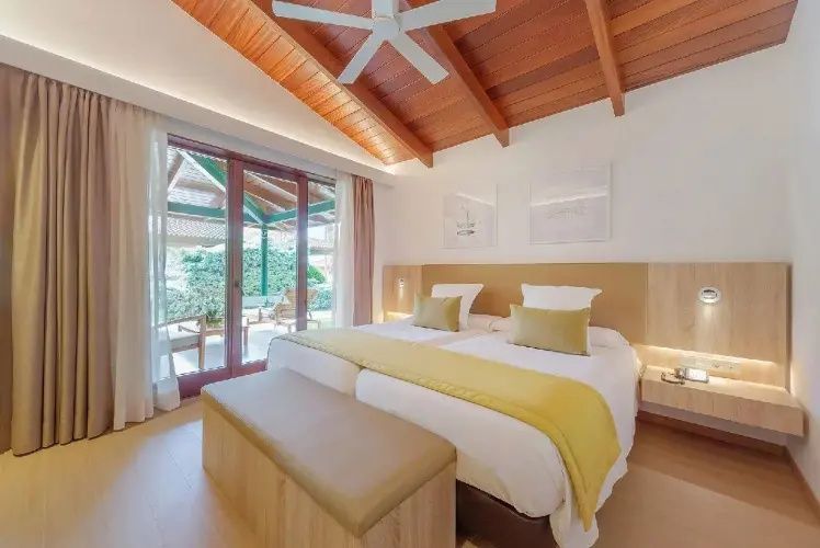 Helles Schlafzimmer mit Doppelbett, Holzdecke und Balkontür zur Terrasse.