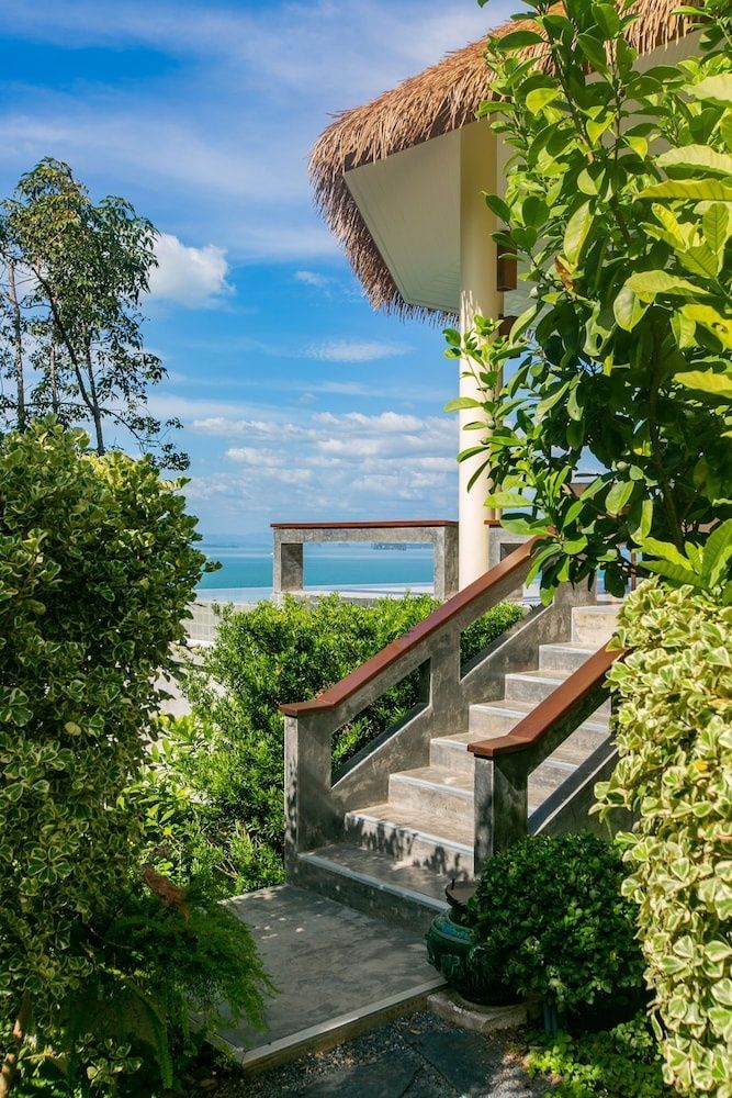 Betontreppe im Außenbereich der Anlage, umgeben von grünen Pflanzen und mit Blick aufs Meer.
