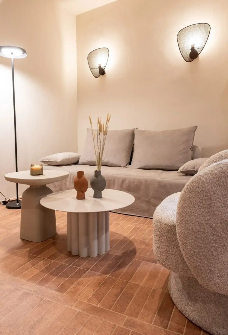 Wohnbereich einer Suite mit hellem Sofa, runden Beistelltischen und Sessel.