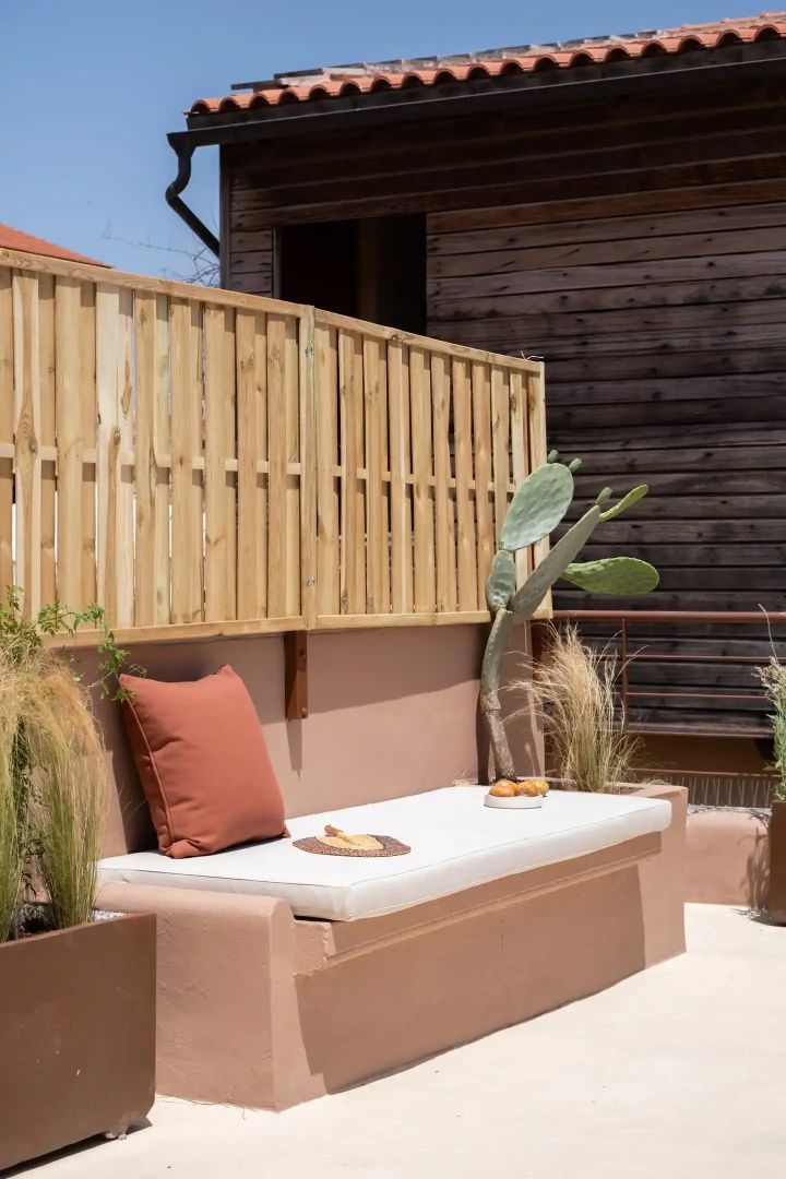 Eingebaute Sitzbank auf der Terrasse mit weißem Polster und Holzschutzzaun.