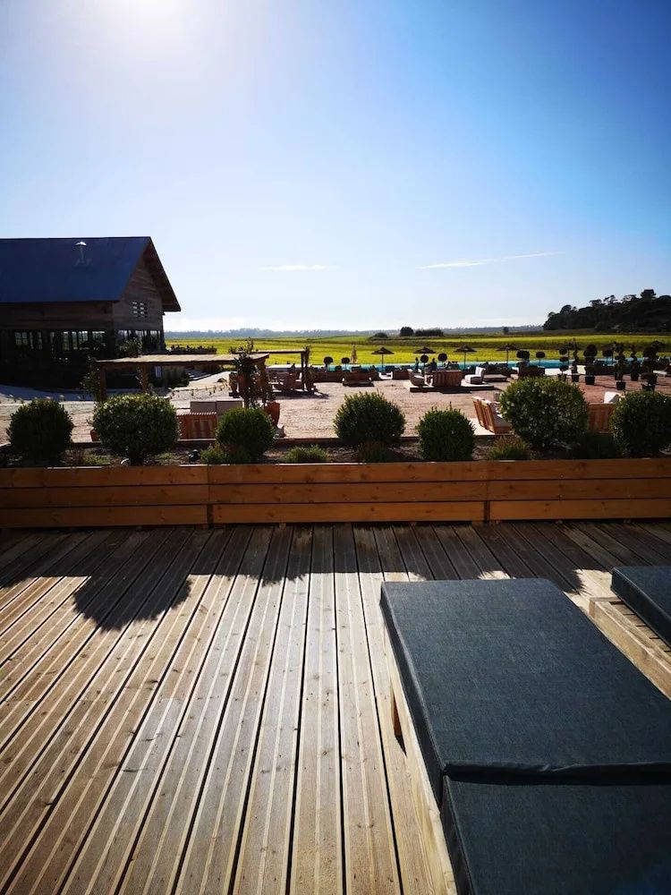 Sonnige Holzterrasse mit Liegestühlen und Blick auf die umliegende Natur.