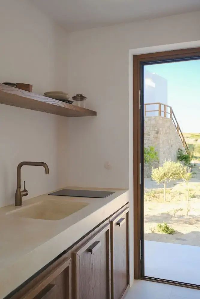 Küchenzeile mit geöffneter Tür und Blick auf die sonnige Landschaft von Milos.