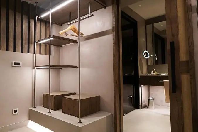 Offenes Kleiderschranksystem mit Holzregalen und integrierter Beleuchtung im Zimmer.