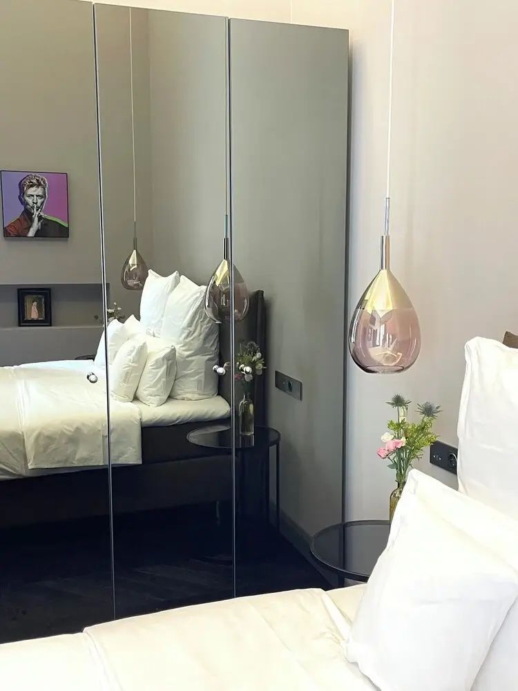 Spiegelwand im Schlafzimmer spiegelt ein Doppelbett, eine Hängelampe und ein Wandbild wider.