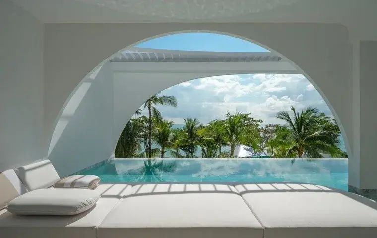 Aussicht von der Liegeflache über einen privaten Pool hin zu Palmen und dem Meer.