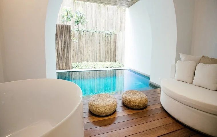Privater Plunge Pool auf der Terrasse mit Holzdeck, Sitzhockern und einer Badewanne.