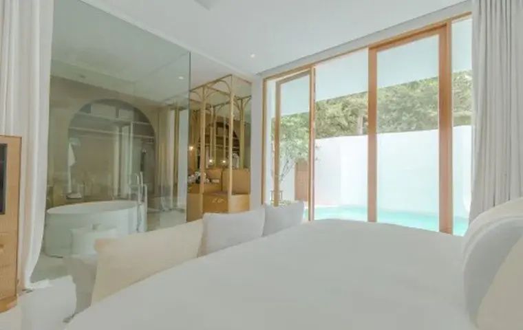 Blick vom Bett durch eine große Glasfront auf die Terrasse mit privatem Außenpool.