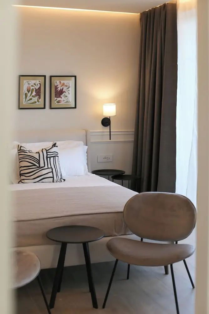 Doppelbett mit beigefarbener Decke, Sessel und Beistelltisch im Zimmer