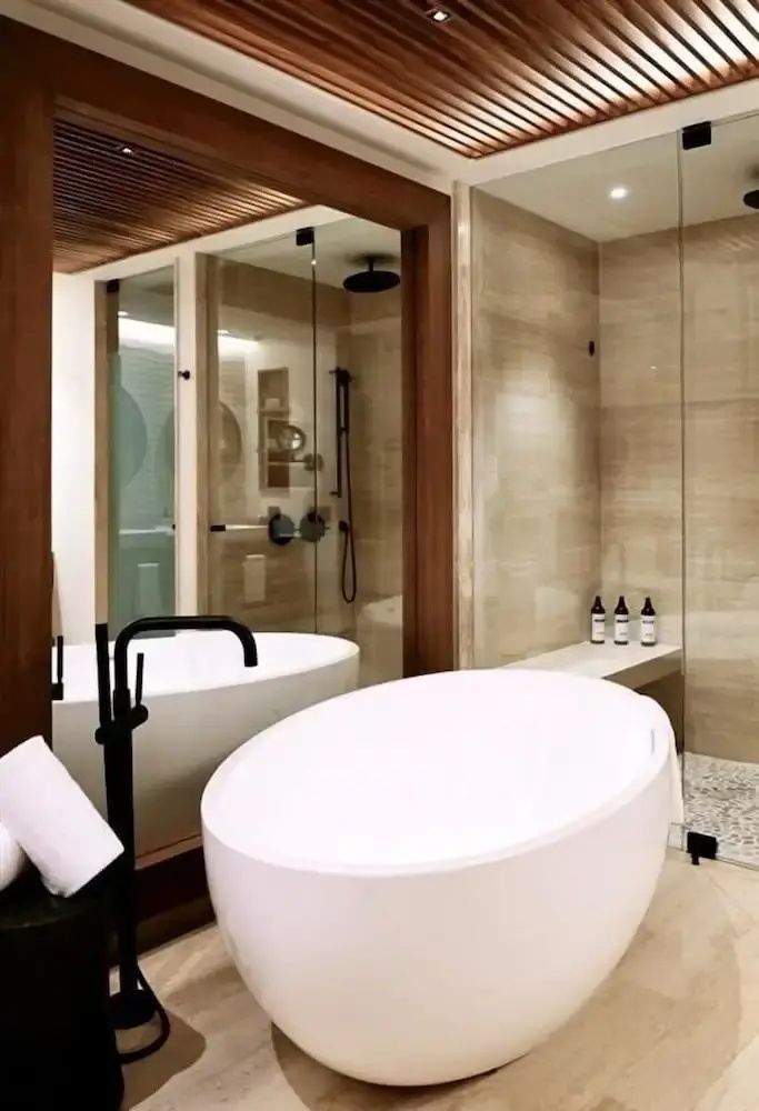 Freistehende weiße Badewanne und eine ebenerdige Dusche mit Glaswand in einem Badezimmer.