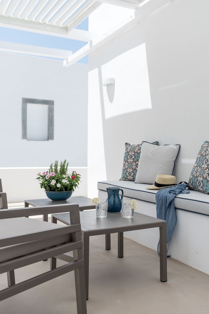 Terrasse mit einer Polsterbank, Kissen, kleinen Tischen und einem Blumenstock.