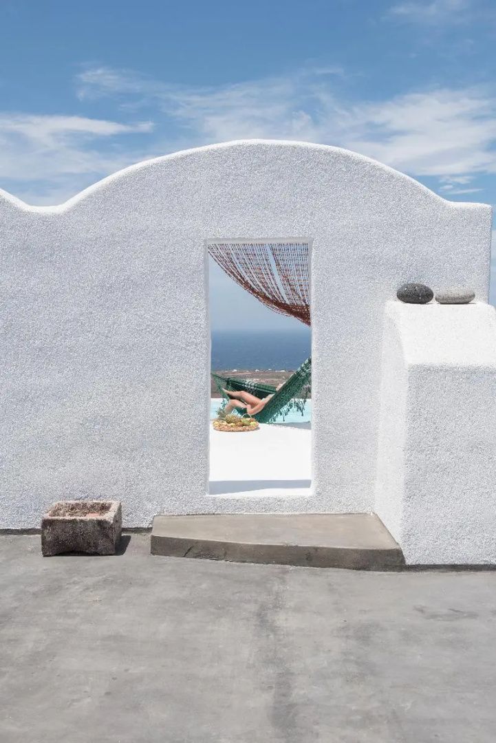 Blick durch einen Wanddurchgang auf eine Terrasse mit Hängematte und Meerblick.