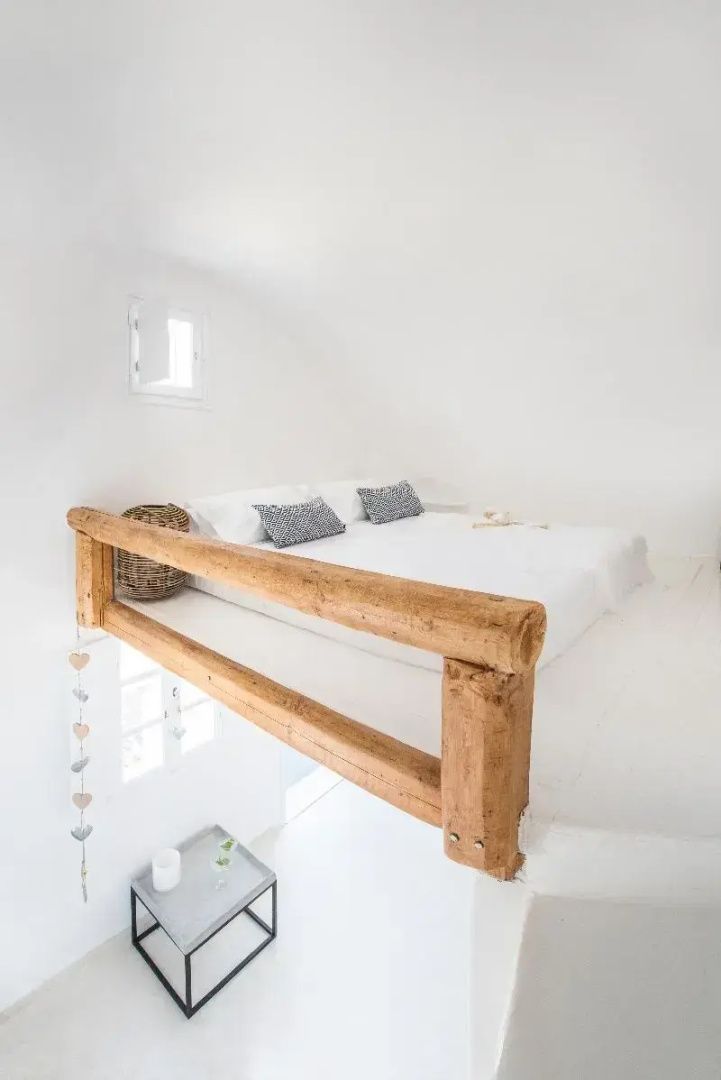 Schlafbereich auf einer Galerie mit weißem Bett und einem Geländer aus Holz.