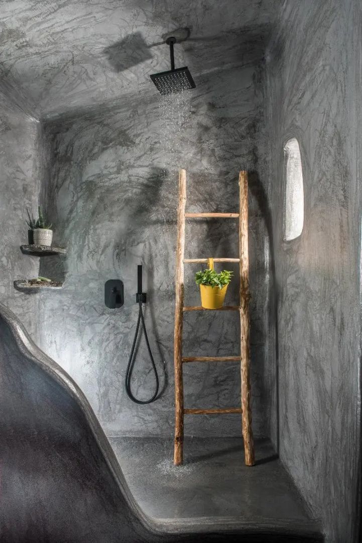 Moderne Dusche mit grauen Betonwänden, schwarzer Armatur und einer Holzleiter als Dekor.