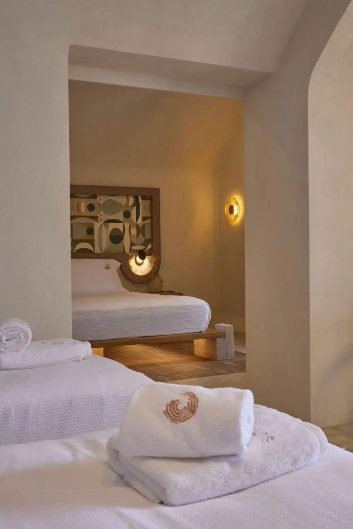 Blick in ein Hotelzimmer mit Doppelbett, Wanddekoration und indirekter Beleuchtung.