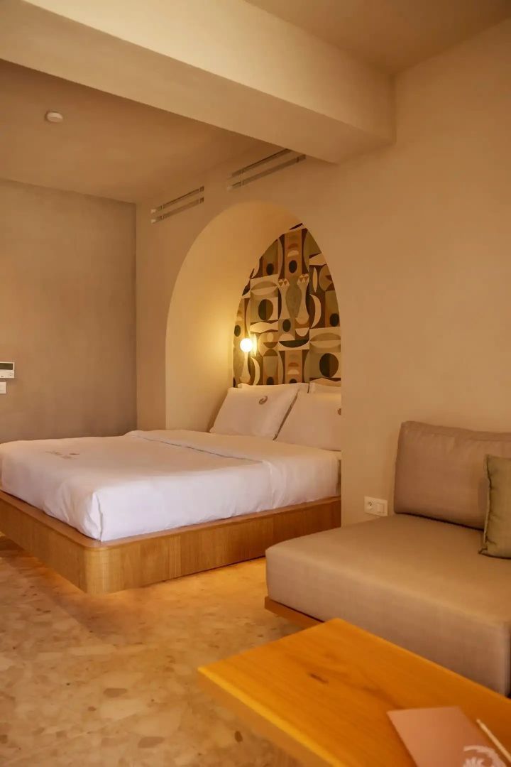 Doppelbett in einer Rundbogennische mit gemusterter Kopfteilwand und seitlichem Sofa.