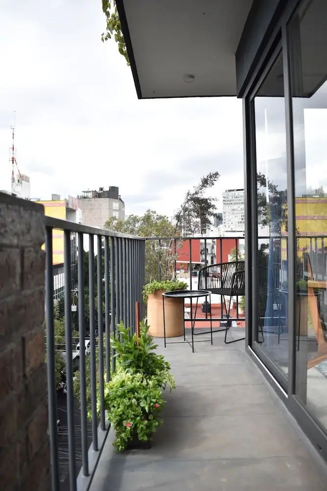 Balkon mit Sitzgelegenheit, Pflanzkübel und Blick auf die Stadt.