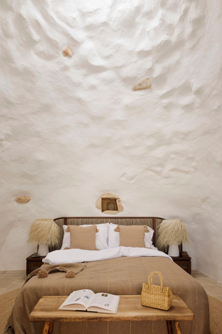 Doppelbett vor einer weiß gekalkten Wand im Trullo Stil mit Lampen aus Naturmaterialien