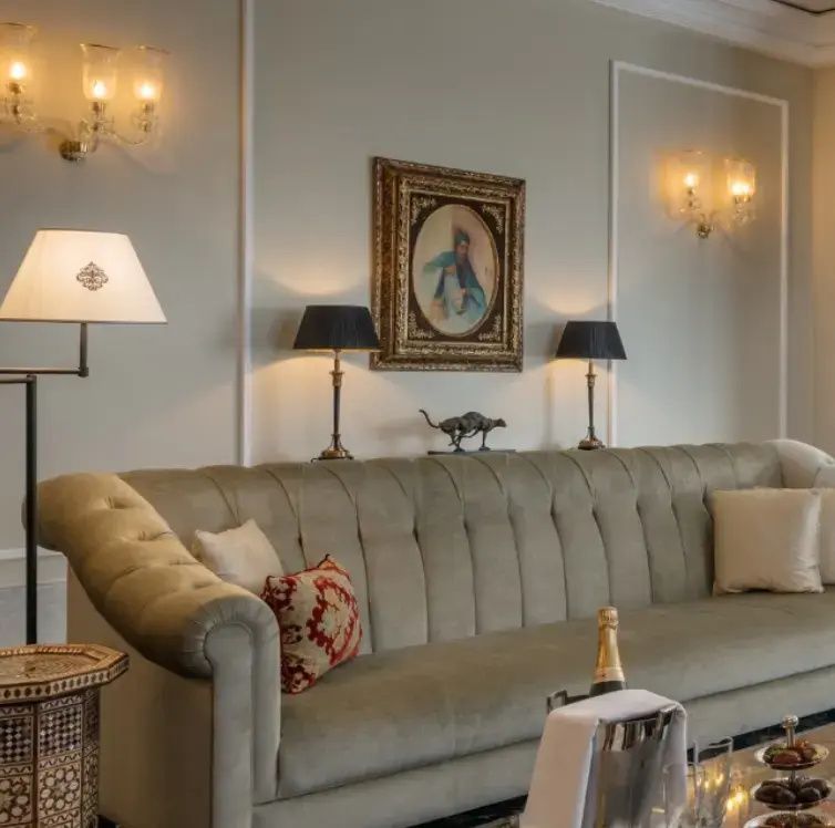 Langes beiges Sofa mit Zierkissen vor einer Wand mit Bild und Lampen.