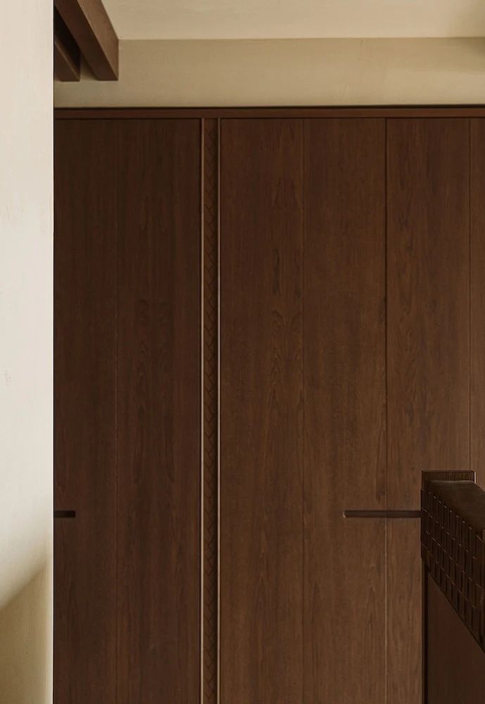 Nahaufnahme einer dunklen Holzwand mit schlichten Griffmulden eines modernen Einbauschranks