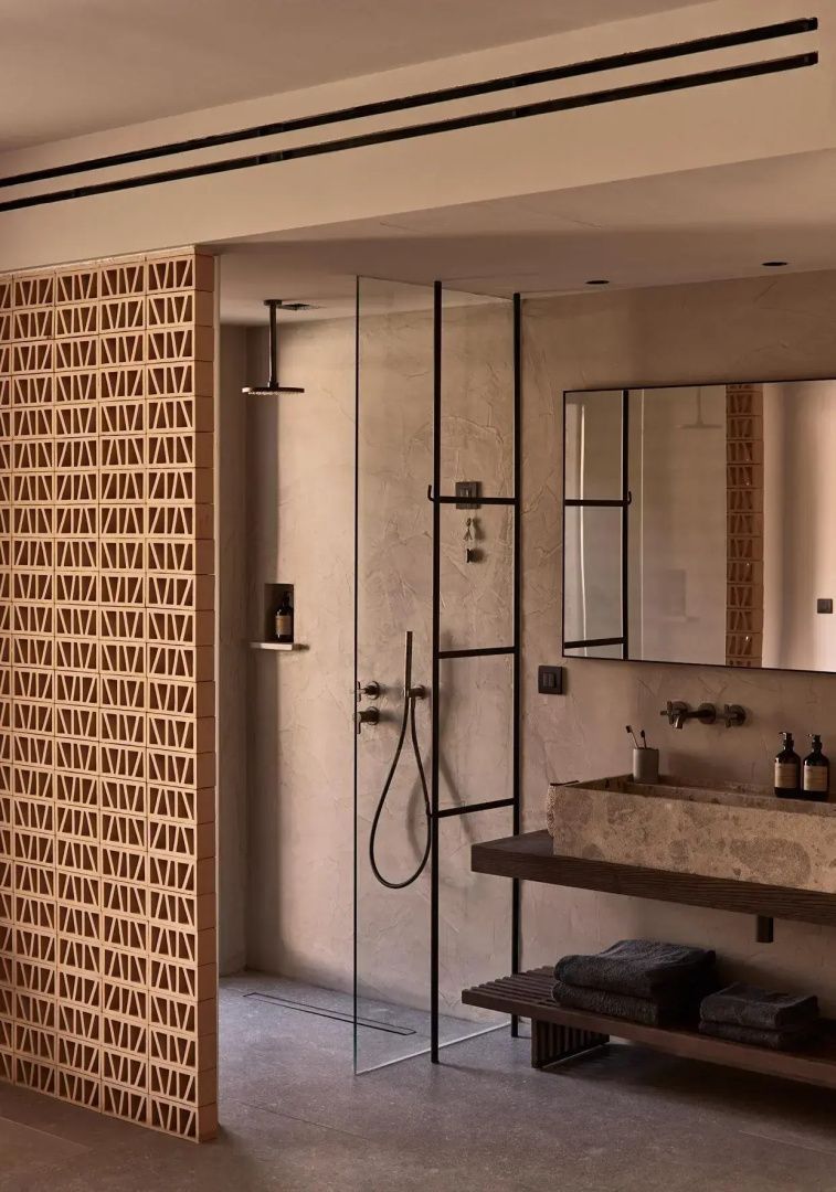 Badezimmer mit begehbarer Dusche, Natursteinwaschtisch und gemusterter Ziegelwand.