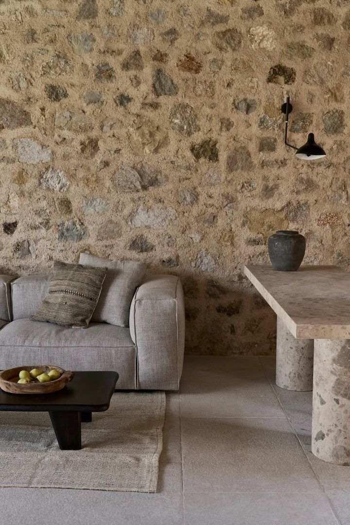 Sitzbereich einer Suite mit hellgrauem Sofa, Couchtisch und einer Wand aus Naturstein.
