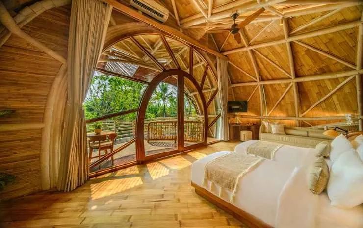 Großes Rundbogenfenster im Schlafzimmer mit Blick auf grüne Bäume und Balkon.