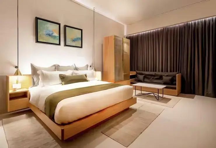 Schlafbereich im Hotelzimmer mit Doppelbett, Schrank und Sitzsofa an der Wand.