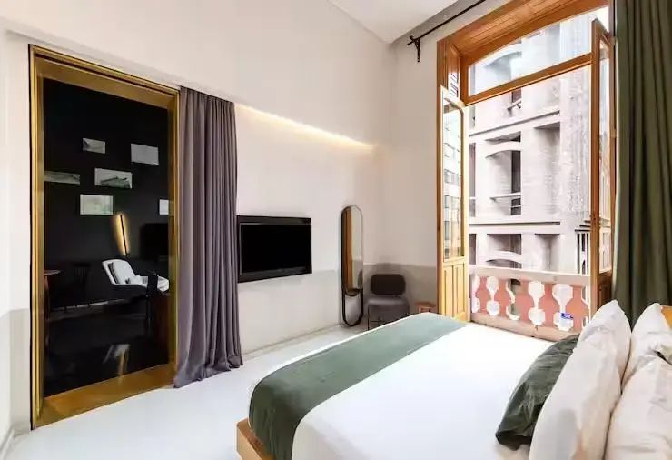 Blick vom Bett auf die Wand mit Fernseher, Spiegel und hohem Balkonzugang.