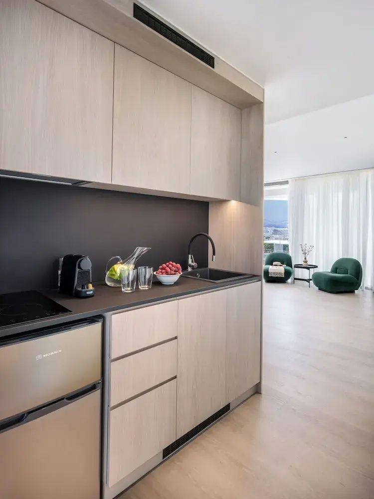 Moderne Küchenzeile in einem Apartment mit hellen Holzfronten, Spüle und Kaffeemaschine.