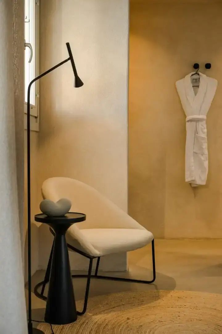 Heller Sessel neben einem kleinen Beistelltisch und einer Stehlampe im Zimmer