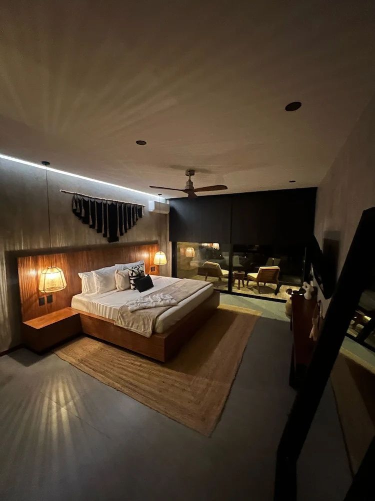 Modernes Schlafzimmer mit Holzdoppelbett, Nachttischlampen und Balkonaussicht bei Nacht.