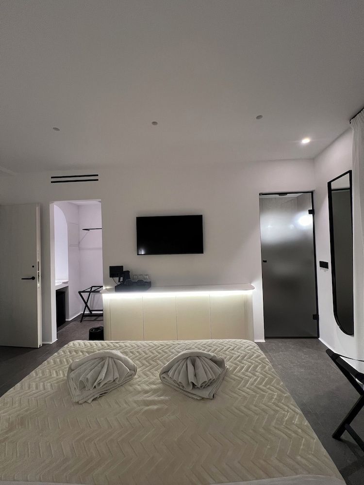Hotelzimmer mit Flachbildfernseher über beleuchteter Anrichte und gefalteten Handtüchern.