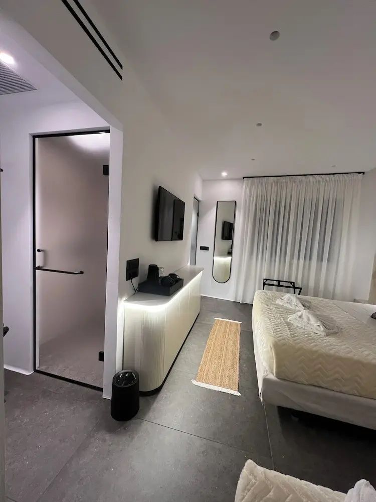 Blick durch das Hotelzimmer mit Glastür, beleuchtetem Sideboard, Fernseher und Bett.