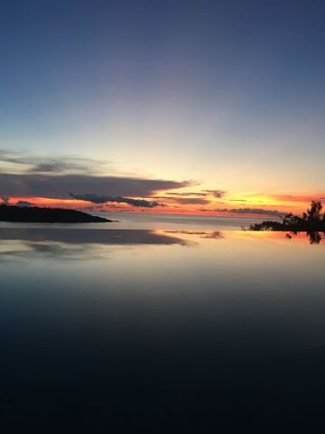 Abendlicher Sonnenuntergang über dem Meer mit Spiegelung auf einer Wasserfläche.
