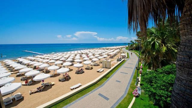 Langer Strand mit Sonnenschirmreihen und türkisem Meer an der Türkischen Riviera bei Side im Oktober