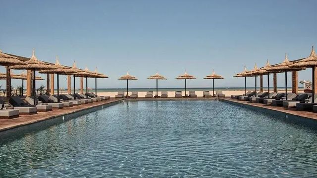Langer Pool mit Reihen von Strohschirmen im Casa Cook El Gouna am Roten Meer