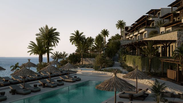 Pool mit Strohschirmen und Palmen im OKU Bodrum über dem Meer